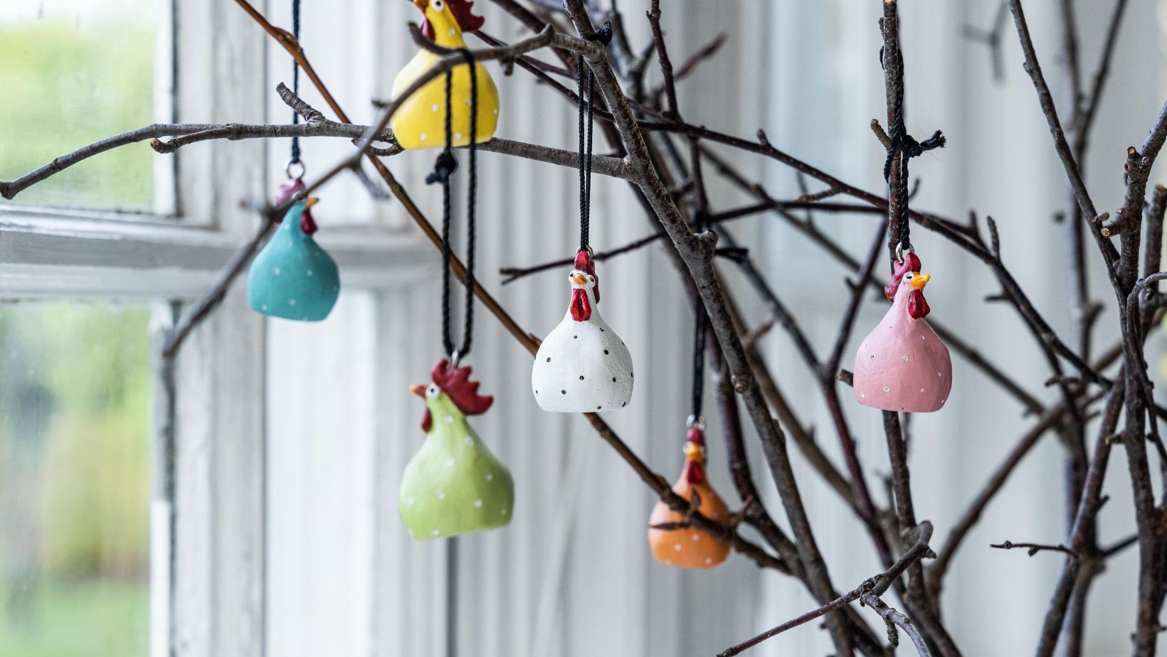 Dekoration für Ostern mit bunten Hühnern von Nääsgränsgarden, die an Ästen hängen.