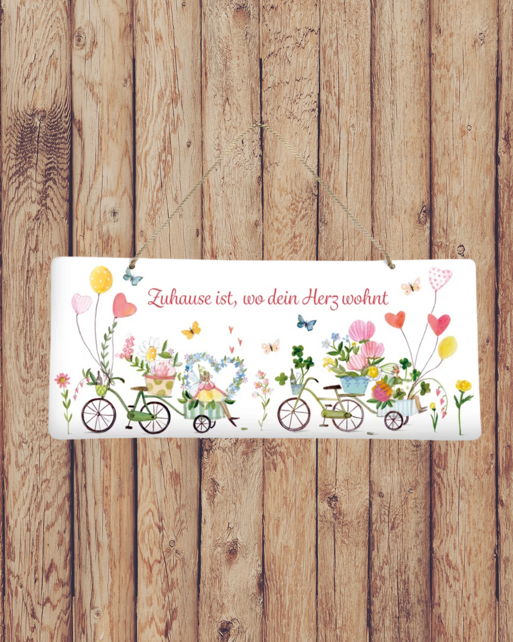Süßes Metallschild Auf ins Glück vom Grätz Verlag vor Holzwand dekoriert, mit Blumen und Fahrrädern als Motiv.