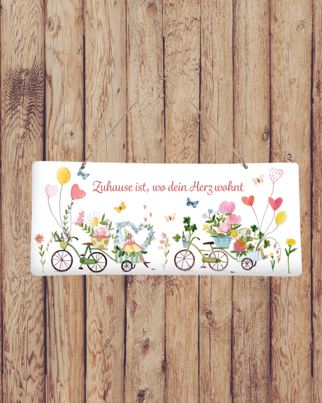 Süßes Metallschild Auf ins Glück vom Grätz Verlag vor Holzwand dekoriert, mit Blumen und Fahrrädern als Motiv.