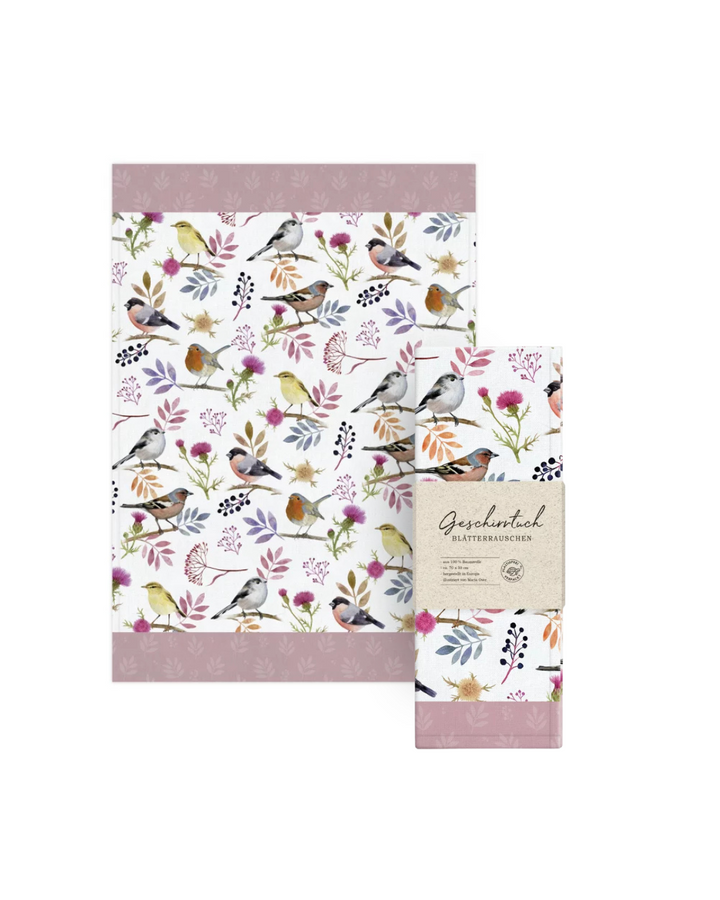 Geschirrtuch Blätterrauschen vom Grätz Verlag mit Verpackung. Zu sehen sind Vögel und Blätter auf weißem Hintergrund, illustriert von Maria Over.