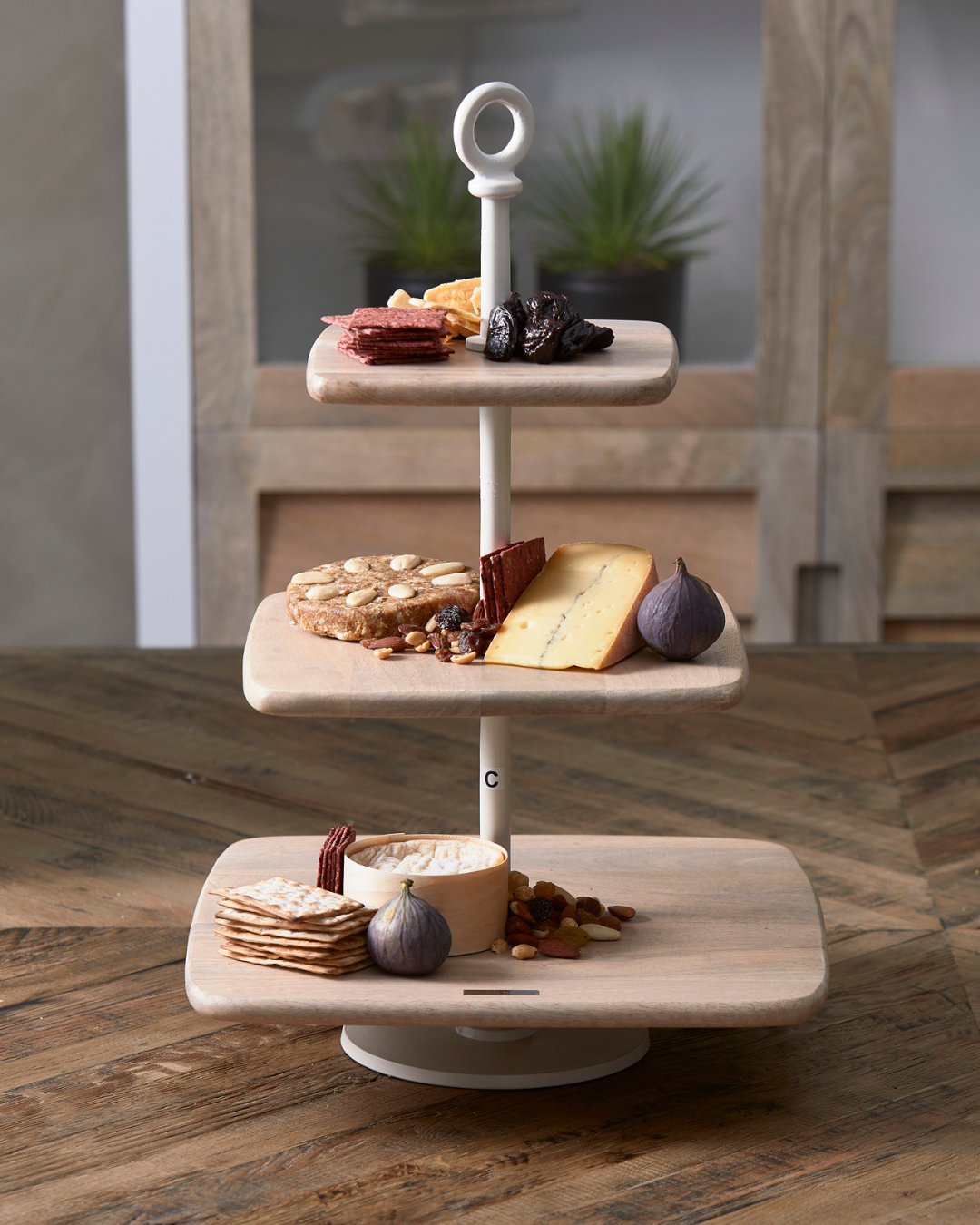 Die Côte Des Basques Etagère von Rivièra Maison ist auf einem Holztisch mit verschiedenem Essen dekoriert.