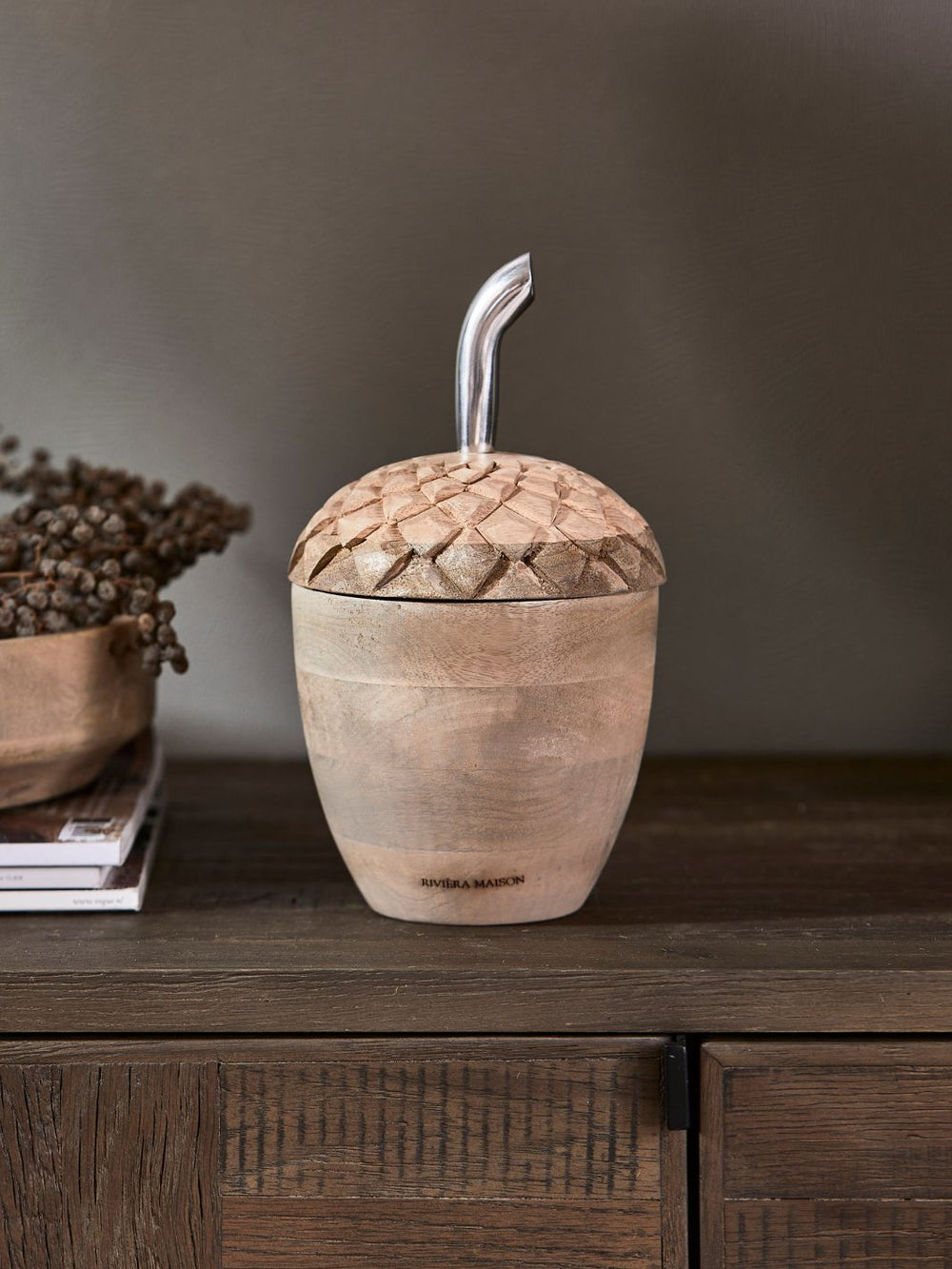 Dekorative Eichel-Dose von Rivièra Maison auf einem Holztisch mit getrockneten Beerenzweigen.