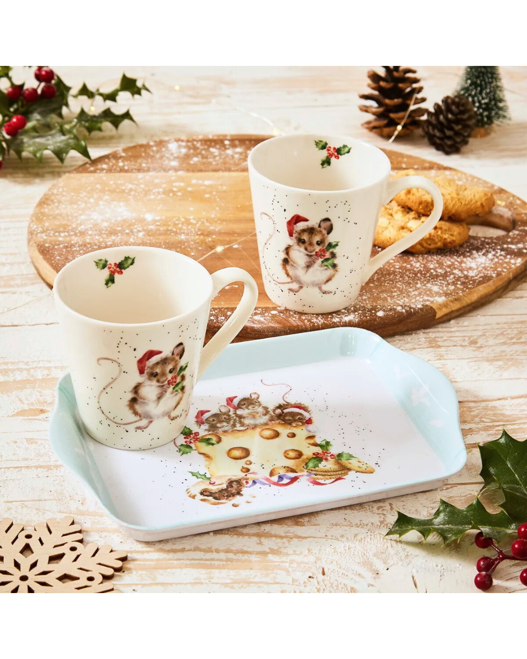 Dekorierte Szene mit dem „Holly Jolly“-Tassen- und Tablett-Set von Wrendale Designs auf einem Holztisch mit Gebäck und Tannenzweigen.