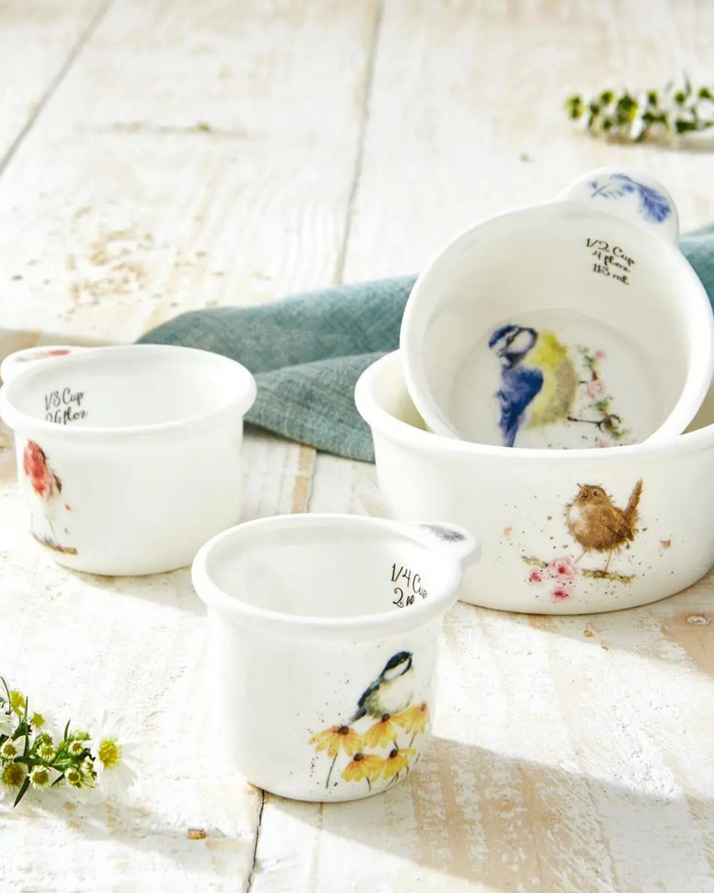 Porzellan Messbecher Vögel von Wrendale Designs, dekorativ auf einem Holztisch mit Küchenutensilien arrangiert. Jeder Becher zeigt eine andere Vogelillustration von Hannah Dale.