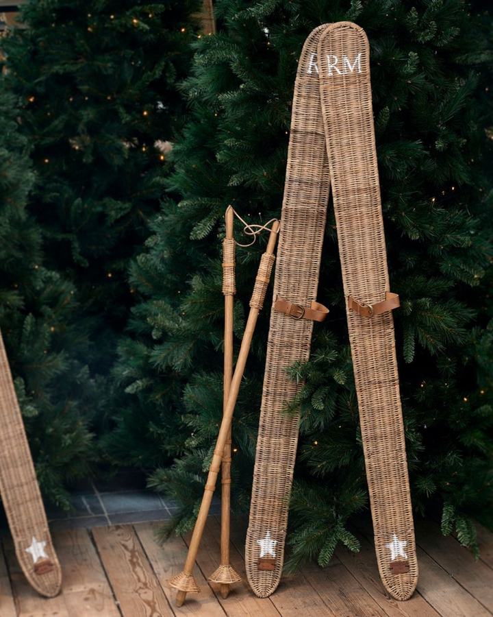 Vor einem Tannenbaum dekorierte Rustic Rattan Ski und Stöcke von Rivièra Maison.