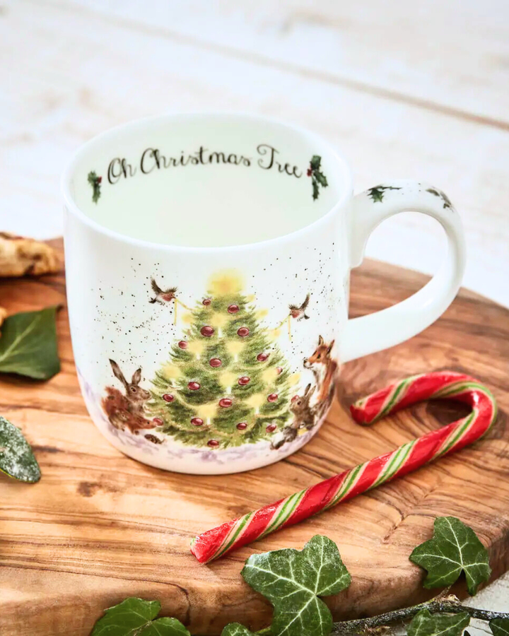 Dekorierte Szene mit der Weihnachtsbaum-Tasse „Oh Christmas Tree“ auf einem Holztisch mit einer Zuckerstange und Waldgrün.