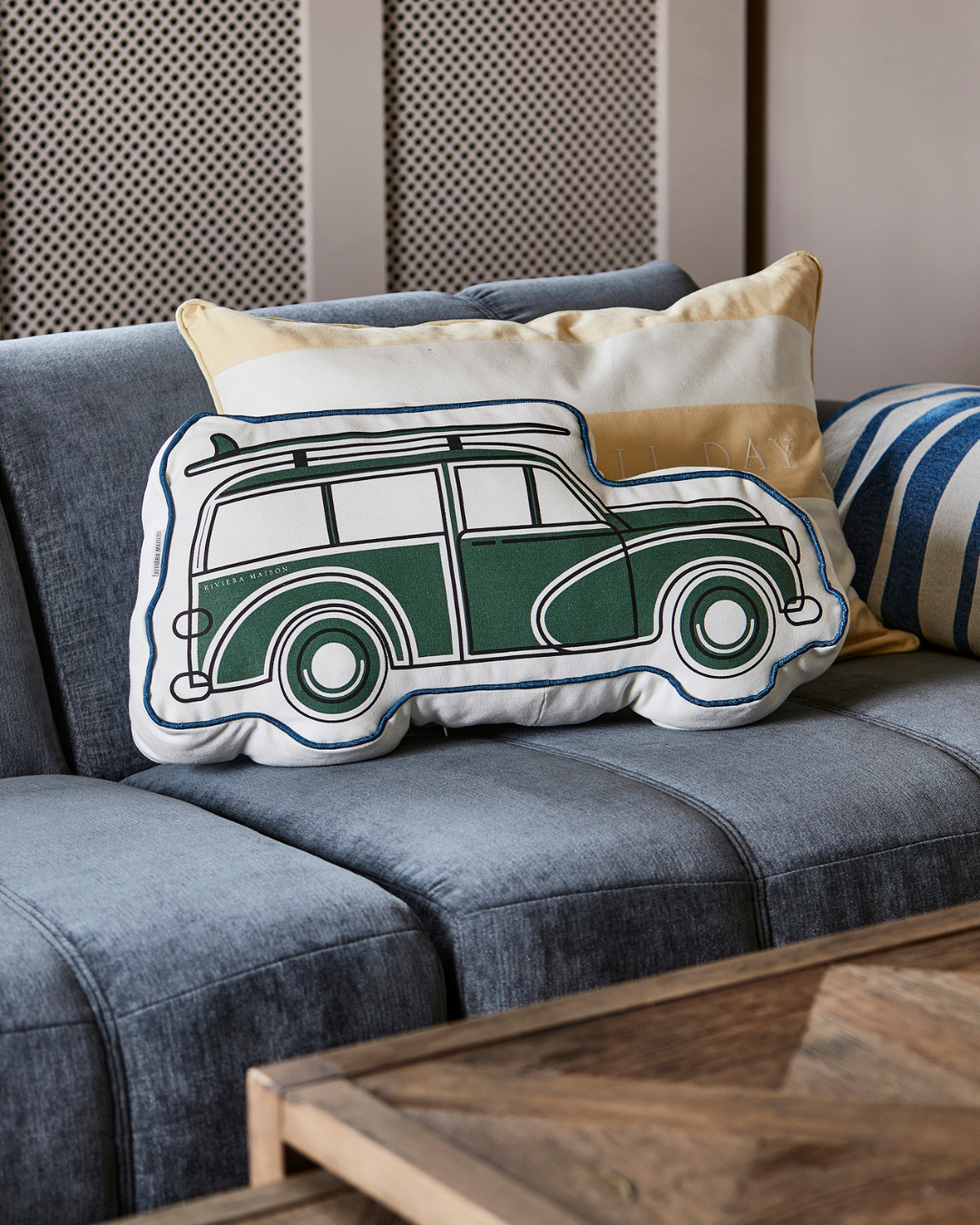 Dekoriertes Roadtrip Box Kissen von Rivièra Maison auf einer blauen Couch.