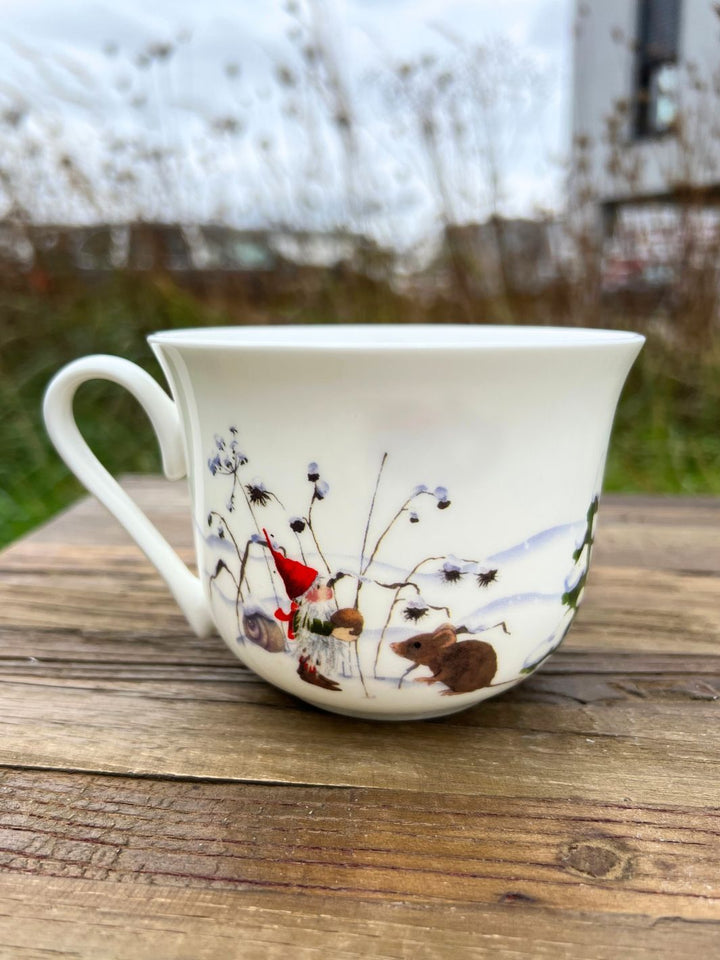 Grätz Verlag Weihnachtswichtel Lieblingstasse aus Porzellan auf braunem Tisch in einem Garten.