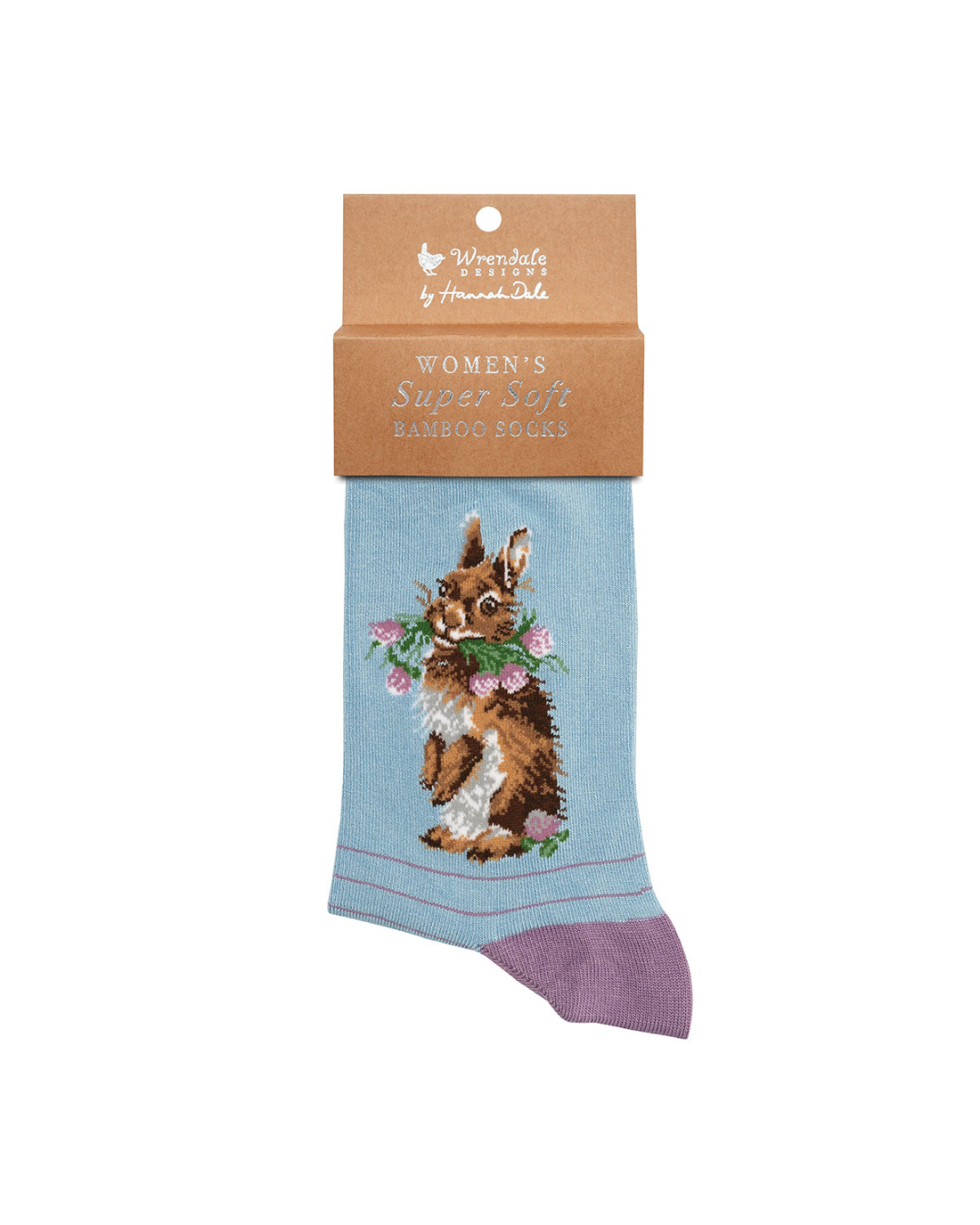 Lila blaue Socken mit einem Hasen als Motiv, der Blumen im Maul hat, von Wrendale Designs mit der braunen Verpackung vor weißem Hintergrund.