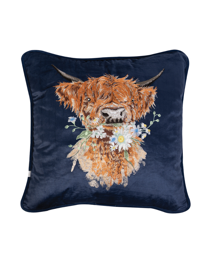 Dunkelblaues Kissen aus Samt mit aufgesticktem Hochland Kuh-Motiv Daisy Coo von Wrendale Designs auf weißem Hintergrund.