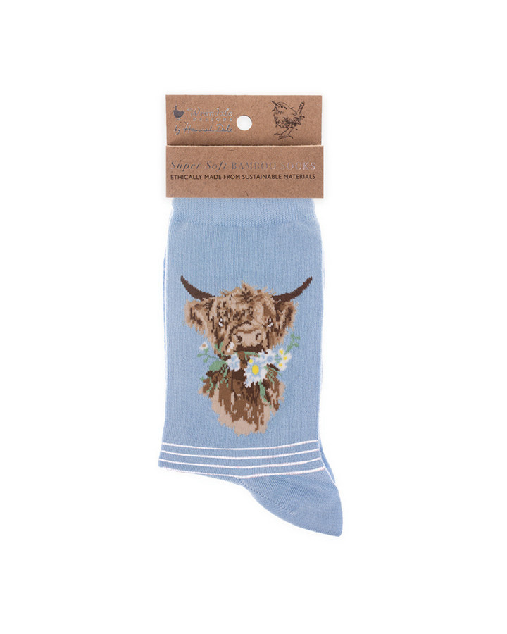 Hellblaue Hochland Kuh Socken von Wrendale Designs mit der braunen Verpackung vor weißem Hintergrund.
