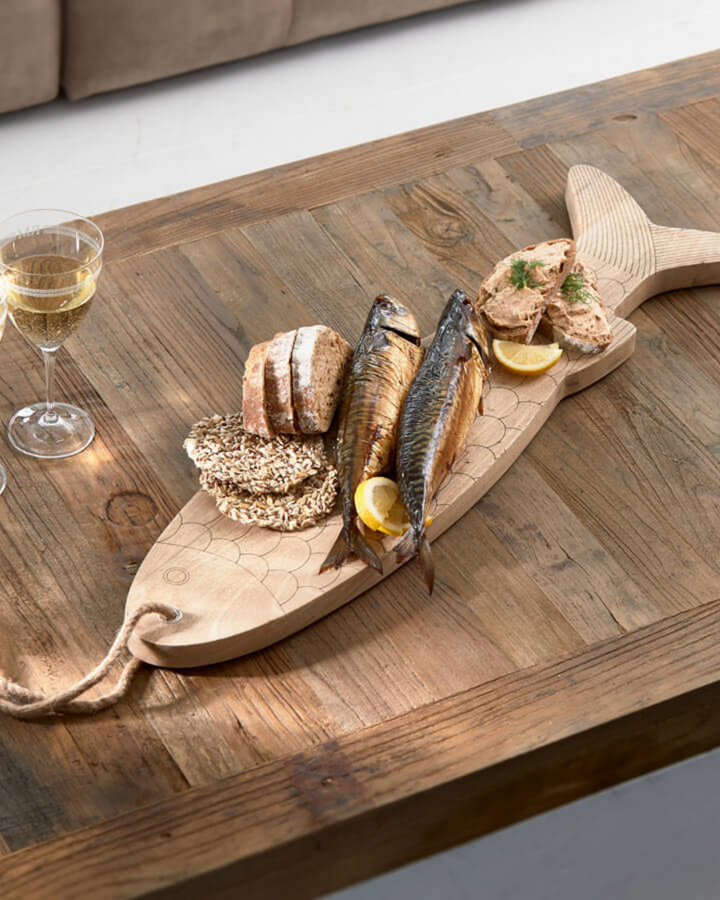 Fisch Schneidebrett von Rivièra Maison auf einem Holztisch, dekoriert mit Brot, geräuchertem Fisch, Zitronenscheiben und einem Glas Weißwein.