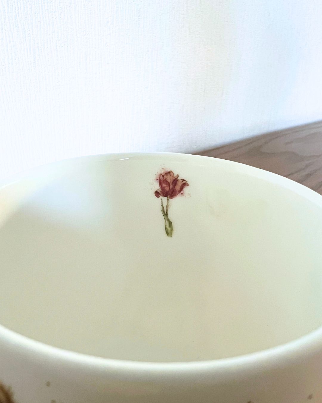 Als Innenmotiv der Kälbchen Tasse von Wrendale Designs ist eine einzelne Tulpeabgebildet.