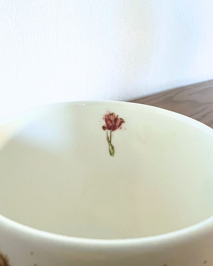 Als Innenmotiv der Kälbchen Tasse von Wrendale Designs ist eine einzelne Tulpeabgebildet.