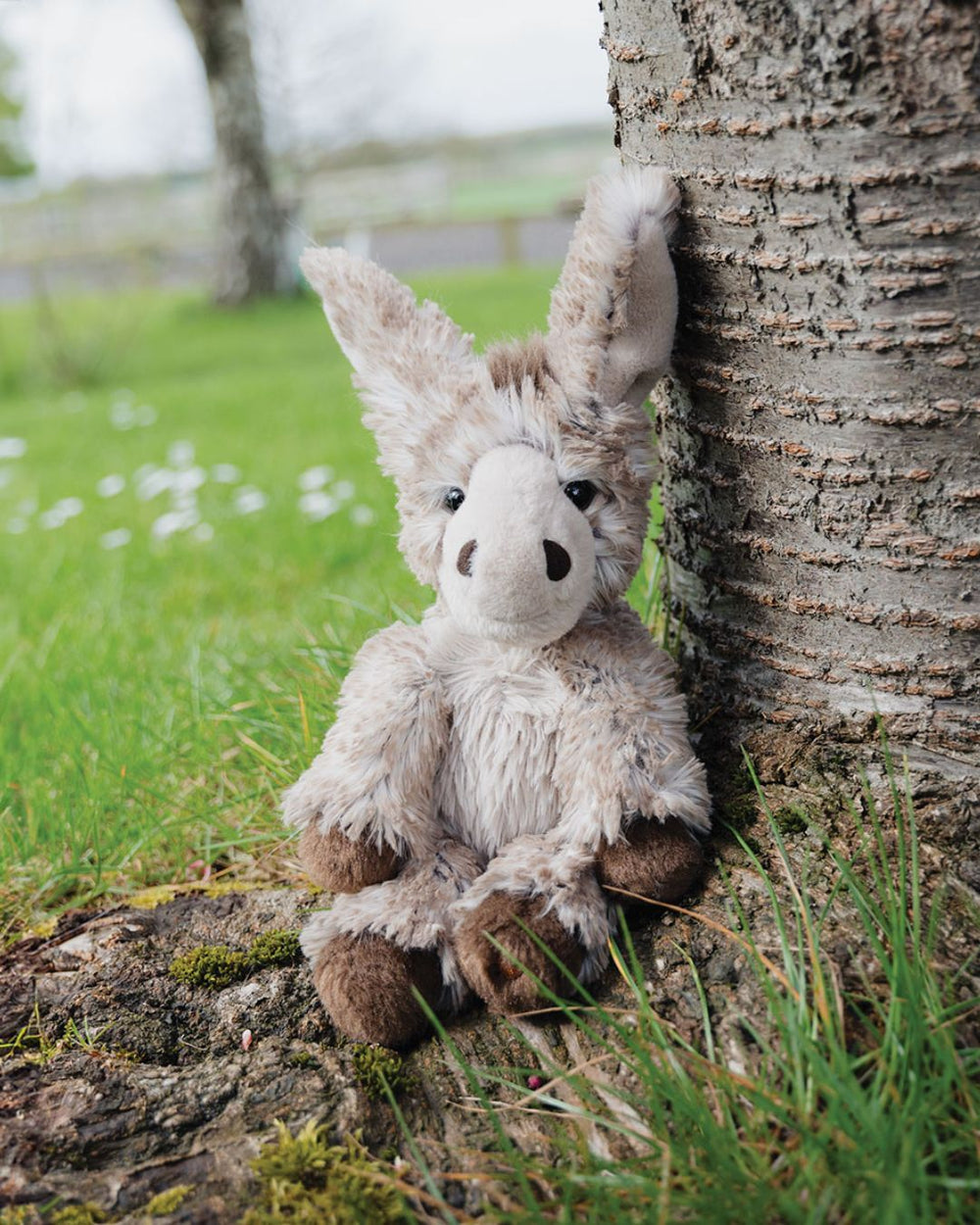 Jack das kleine Esel Kuscheltier von Wrendale Designs in der Größe M sitzt ganz flauschig unter einem Baum.
