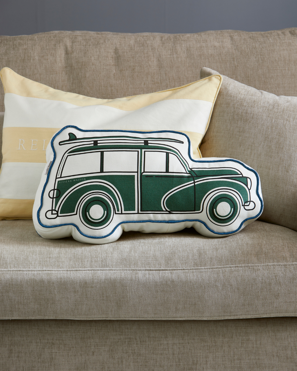 Das Kissen Roadtrip Box Pillow von Rivièra Maison ist mit einem gelb-weiß gestreiften Kissen auf einer beigen Couch dekoriert.