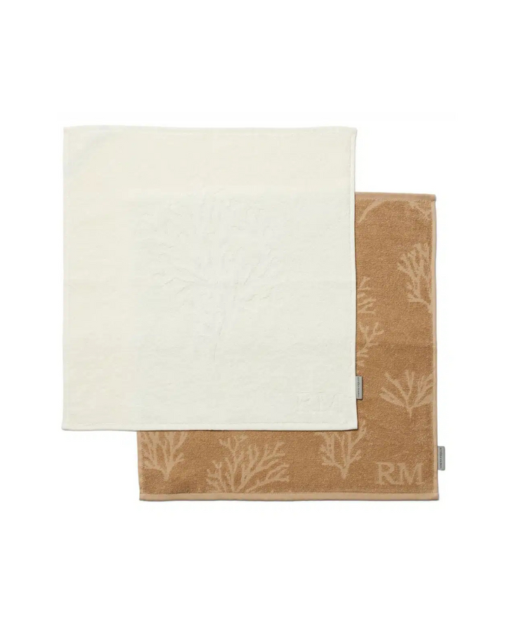 Zwei Küchenhandtücher aus Baumwolle von Rivièra Maison, Modell Coral Reef, eines in Cremeweiß, eines in Sandfarbe, mit eingewebtem Korallenmuster, flach nebeneinandergelegt vor weißem Hintergrund.