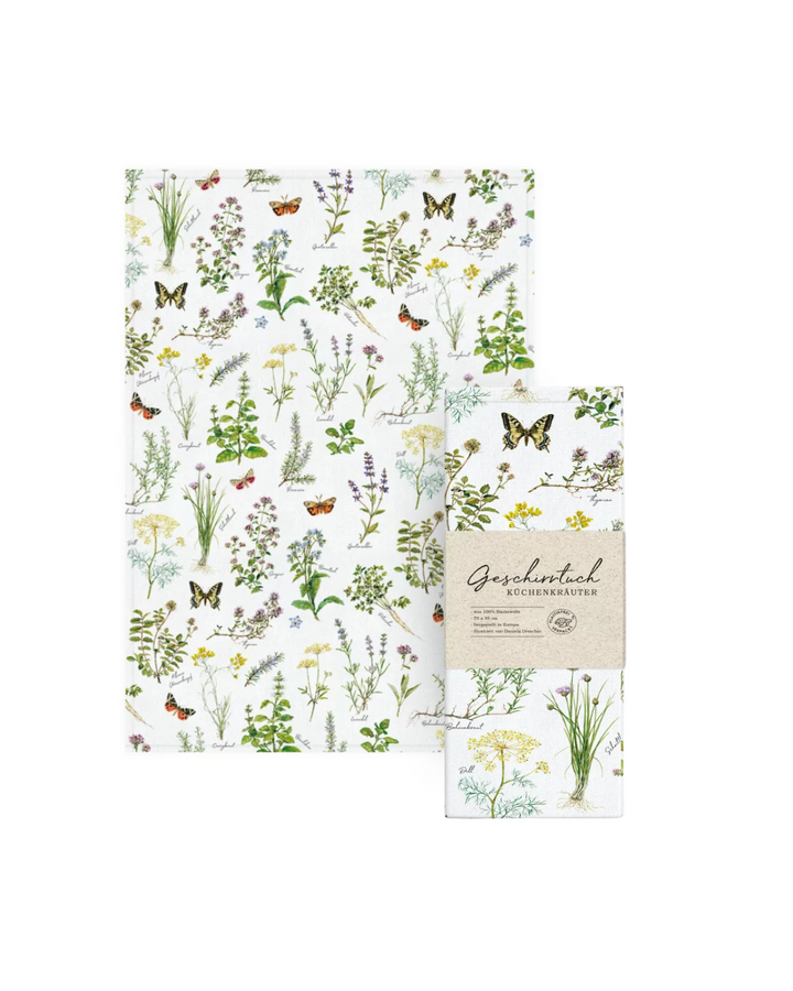 Geschirrtuch Kräuter vom Grätz Verlag neben der passenden Verpackung mit Sicht auf das gesamte Motiv, das verschiedene Kräuterarten und Schmetterlinge zeigt.
