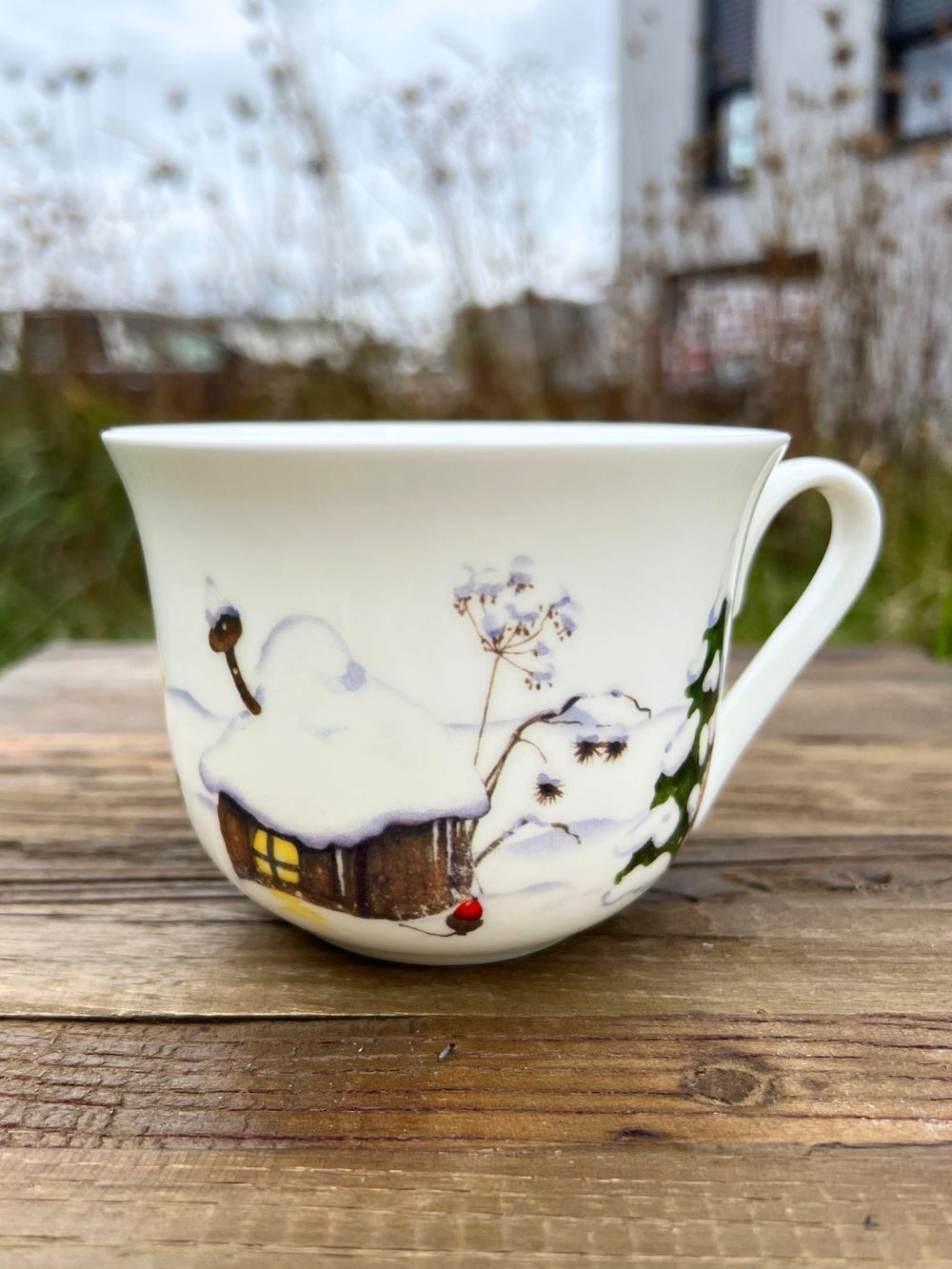 Lieblingstasse mir Weihnachtswichtel Motiv vom Grätz Verlag auf braunem Tisch in einem Garten.