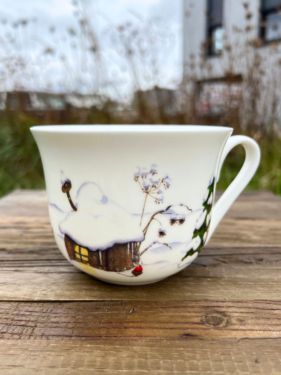 Lieblingstasse mir Weihnachtswichtel Motiv vom Grätz Verlag auf braunem Tisch in einem Garten.