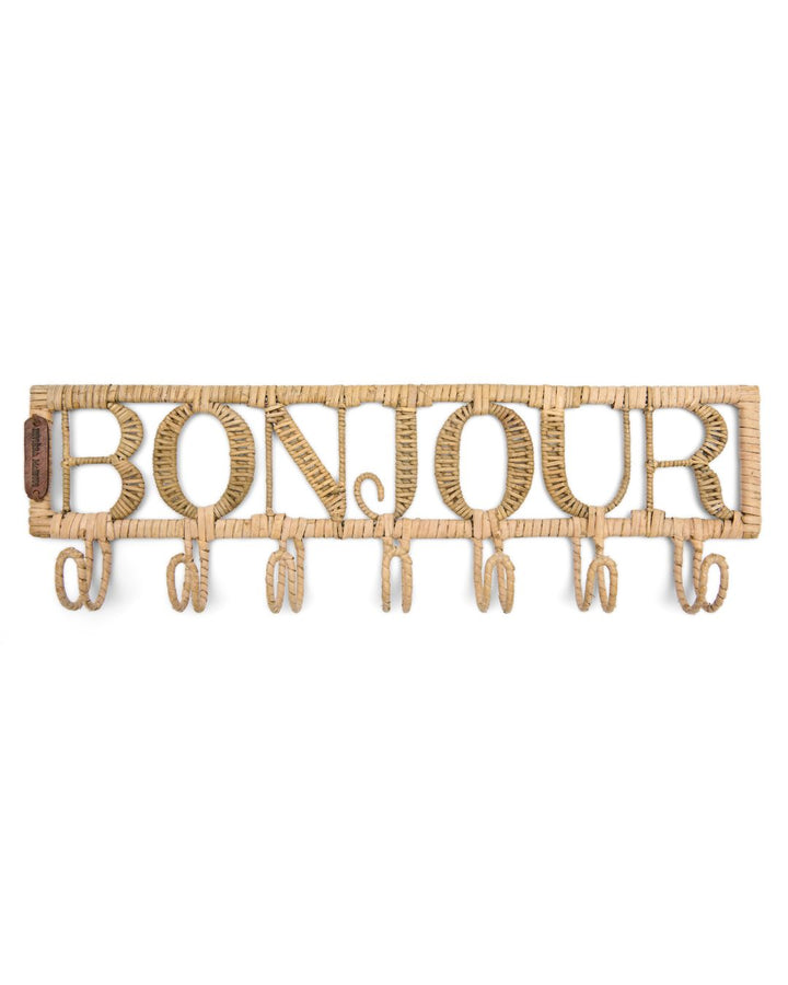Diese Garderobe aus Rattan von Rivèra Maison besteht aus dem Schriftzug Bonjour und sieben Haken, die darunter angebracht sind.