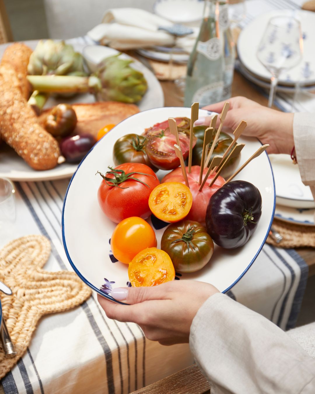 Die Rivièra Maison Servierplatte Como Catch mit Tomaten angerichtet wird auf einen sommerlich gedeckten Tisch gestellt.