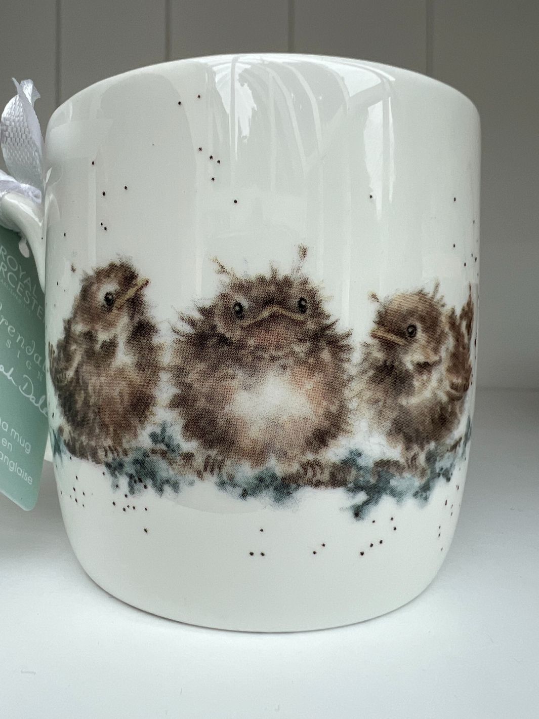 Die Rückseite der Feather your Nest Tasse von Wrendale Designs zeigt drei Vogelkinder auf einem Ast.