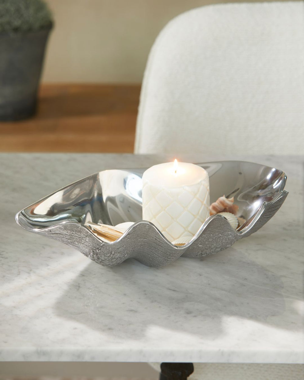 Silberne Muschel Schale für Dekoration von Rivièra Maison steht mit einer Kerze darin auf einem Esstisch.