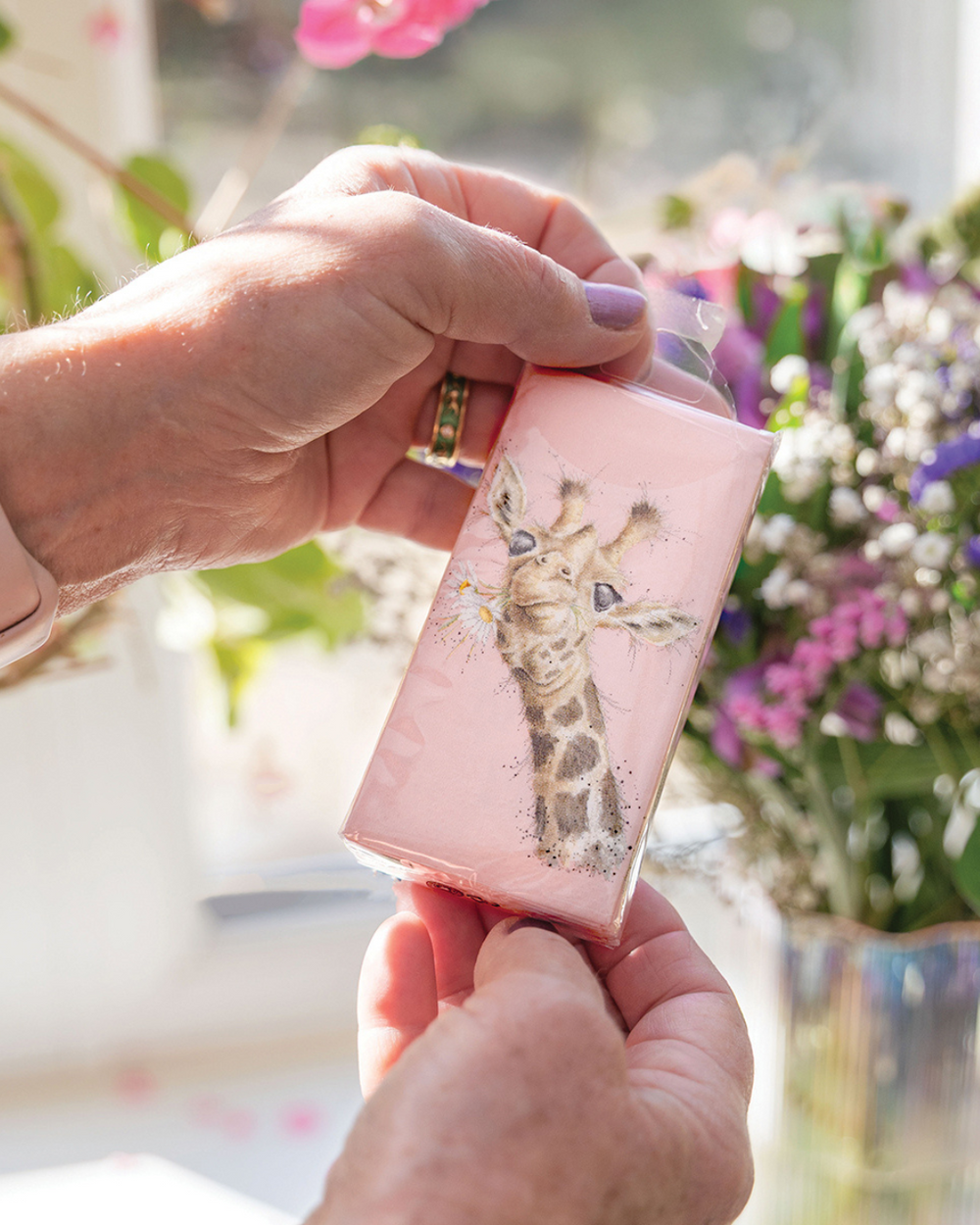 In zwei Händen gehaltene Giraffen Taschentücher von Wrendale Designs mit Margeritenmotiv.