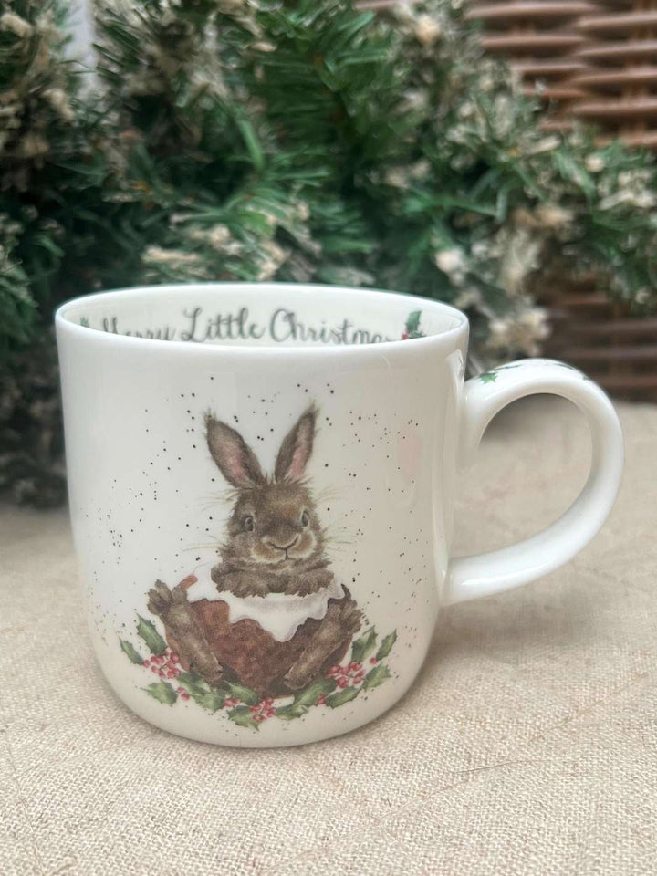 Winterliche Tasse von Wrendale Designs mit einem Hasen im Schnee vor einem weihnachtlichen Hintergrund.