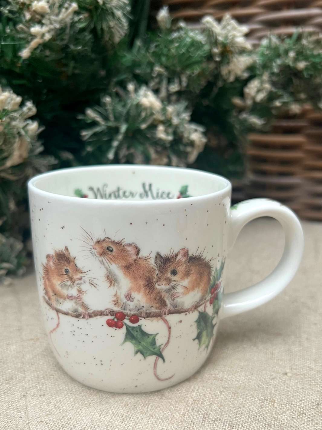 Tasse mit winterlichen Mäusen im Ilex von Wrendale Designs vor einem weihnachtlichen Hintegrund.