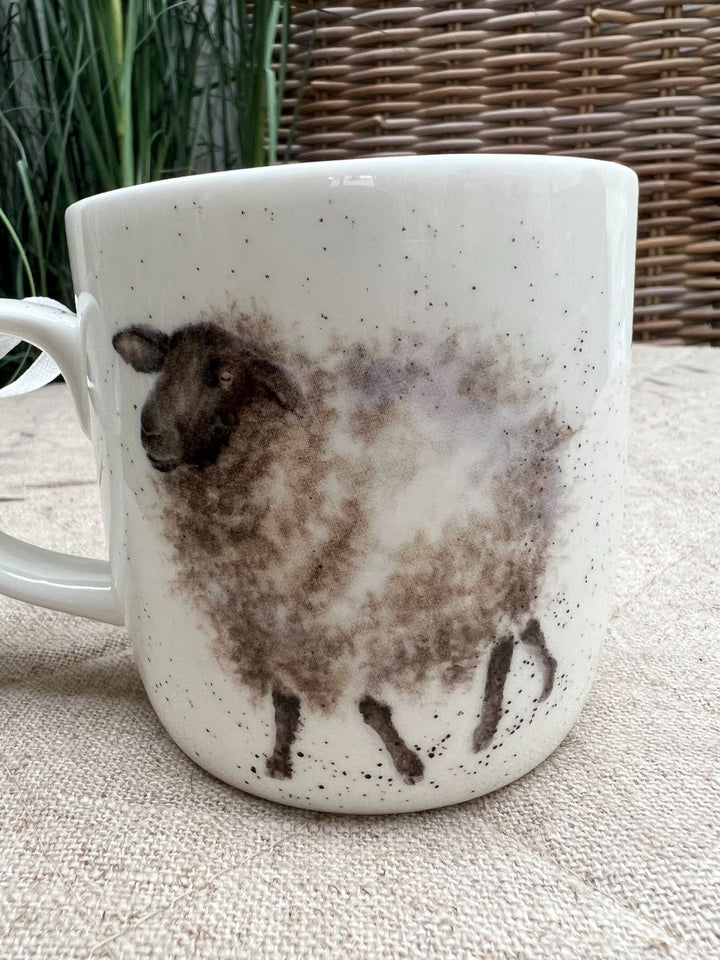 Die Tasse Wooly Jumper von Wrendale Designs zeigt auf der Rückseite ein schwarzes Schaf mit grau-weißem Fell.