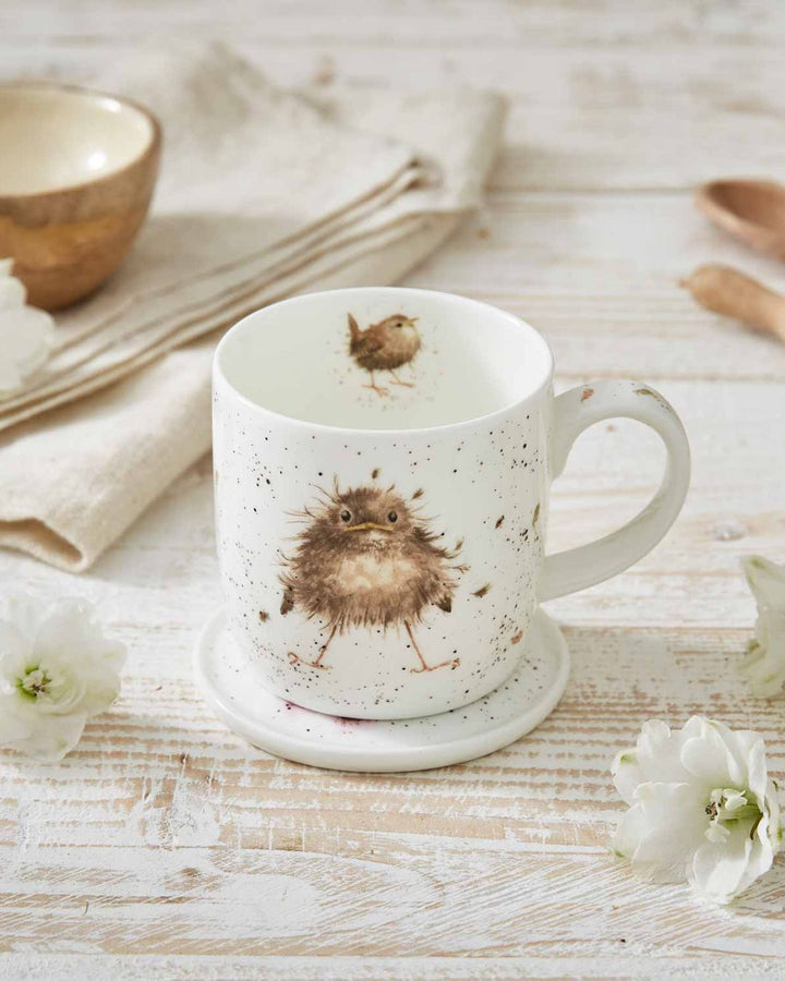 Die Tasse mit dem Piepmatz Vogel Motiv von Wrendale Designs steht auf einem Tisch und nutzt ihren Deckel als Untersetzer.
