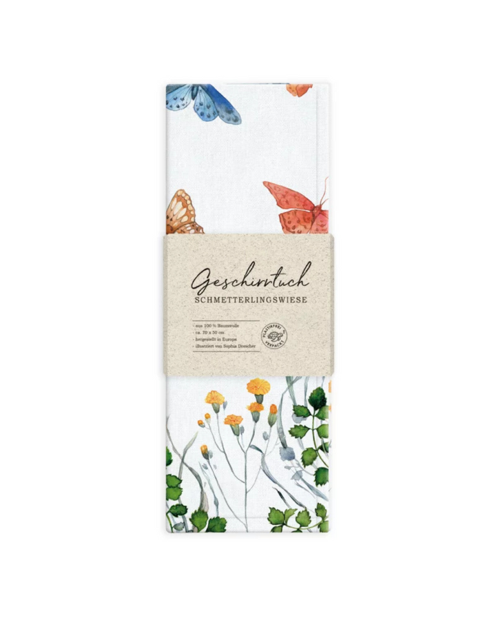 Verpacktes Geschirrtuch „Schmetterlingswiese“ vom Grätz Verlag vor weißem Hintergrund mit Schmetterlings- und Blumen-Illustration von Sophia Drescher.
