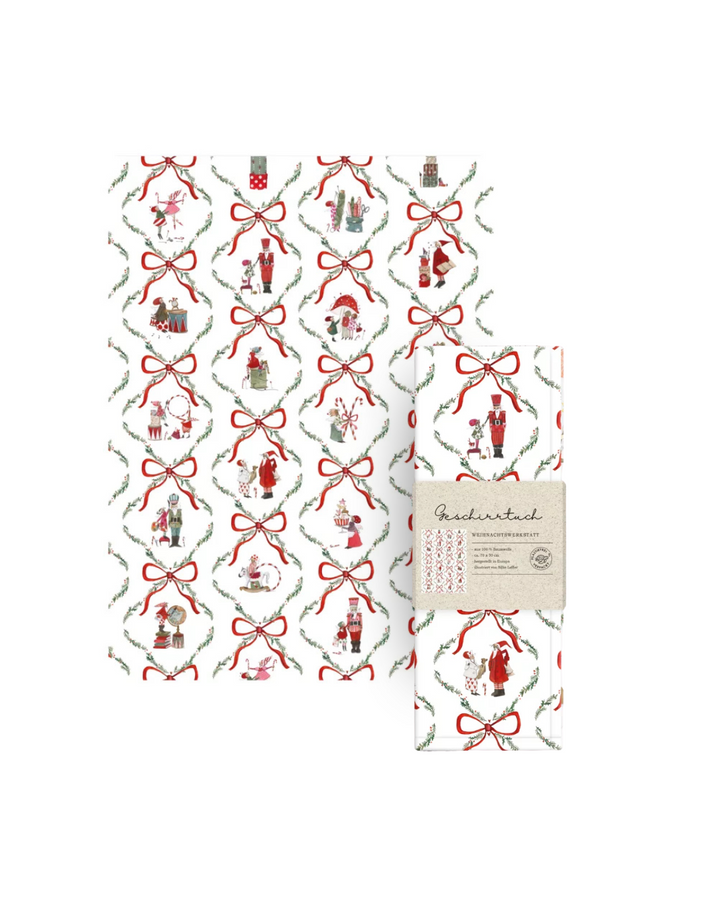 Geschirrtuch und verpackte Variante Weihnachtswerkstatt vom Grätz Verlag mit Illustrationen von Silke Leffler vor weißem Hintergrund. Das Motiv zeigt eine weiße Grundfläche mit roten Schleifen, Tannenzweigen und weihnachtlichen Figuren.