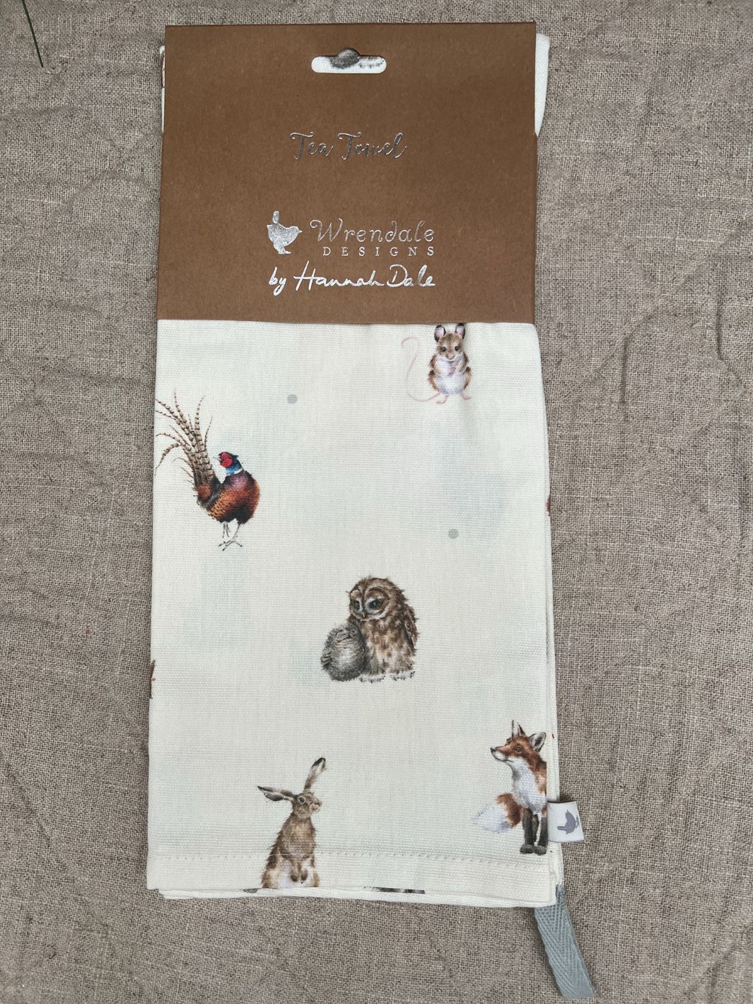 Verpacktes Geschirrtuch Waldtiere von Wrendale Designs auf dunkler Tischdecke.