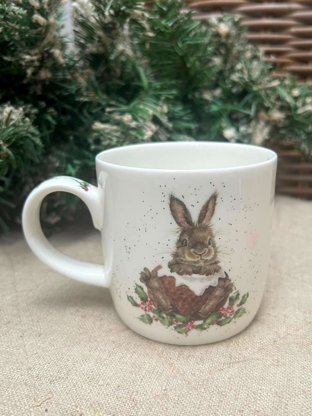 Rückseite der Tasse Hase im Schnee von Wrendale Designs vor weihnachtlichem Hintergrund.