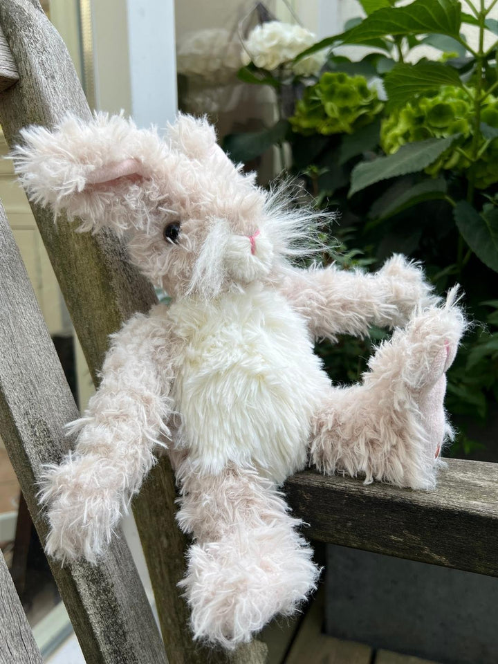 Das große Hasen Kuscheltier Rowan von Wrendale Designs sitzt auf einer Bank im Garten.