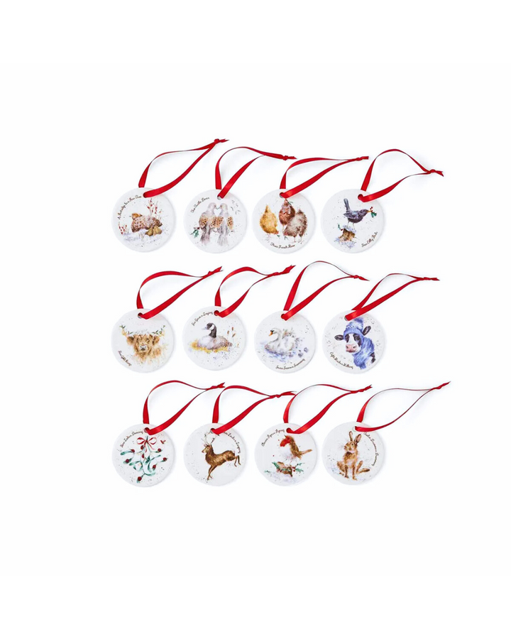 Zwölf Porzellan-Weihnachtsanhänger mit roten Satinbändern aus dem Set 12 Days of Christmas von Wrendale Designs vor weißem Hintergrund.
