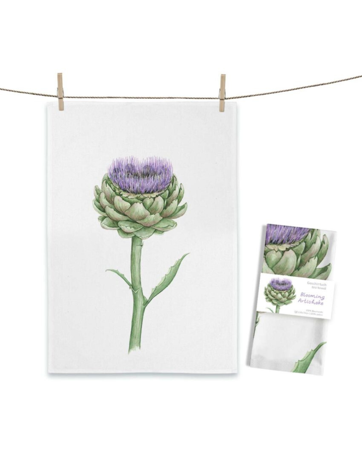 Artischocken Geschirrtuch Blooming Artichoke von Maluu mit blühender Artischocke in Grün und Lila auf weißem Küchentuch an Leine aufgehängt