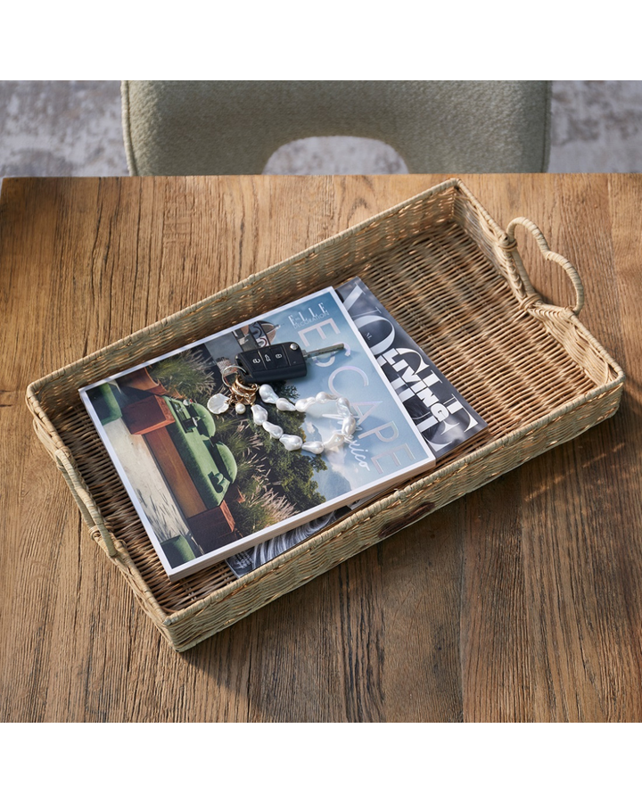 Rustic Rattan Tablett „Happy Heart Tray“ von Rivièra Maison mit Magazin, Schlüssel und Schmuck auf einem Holztisch arrangiert.