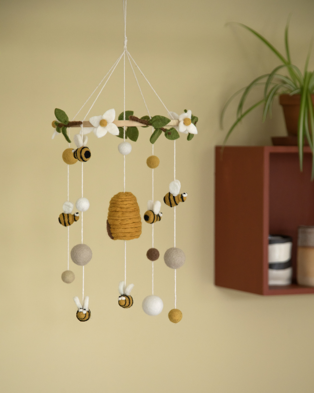 Mobile von Gry und Sif mit Bienen und Bienenstock als Anhänger in einem gekben Kinderzimmer.