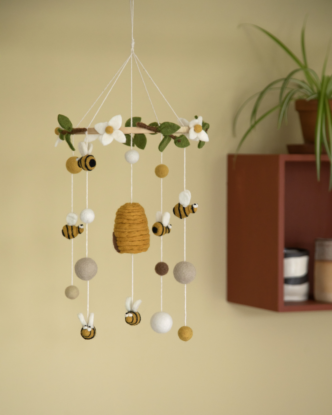 Mobile von Gry und Sif mit Bienen und Bienenstock als Anhänger in einem gekben Kinderzimmer.