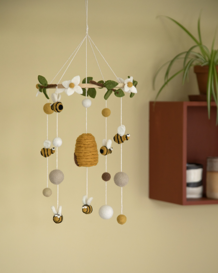 Mobile von Gry und Sif mit Bienen und Bienenstock als Anhänger in einem gekben Kinderzimmer.