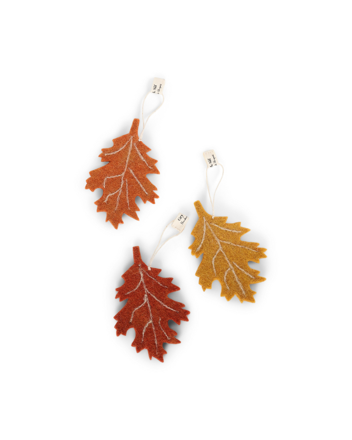Drei herbstliche Filzanhänger in Birkenblatt-Form von Gry & Sif in Currygelb, Orange und Dunkelorange vor weißem Hintergund.