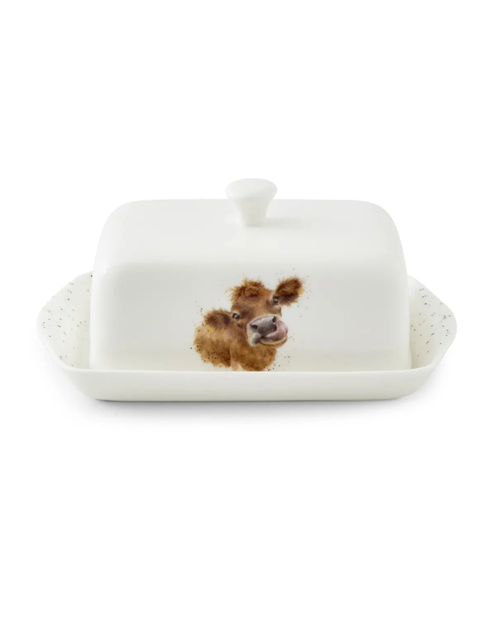 Frontansicht der Kuh Butterdose "Royal Worchester" aus Porzellan von Wrendale Designs vor weißen Hintergrund.  Das Motiv zeigt eine Kuh mit herausgestreckter Zunge.