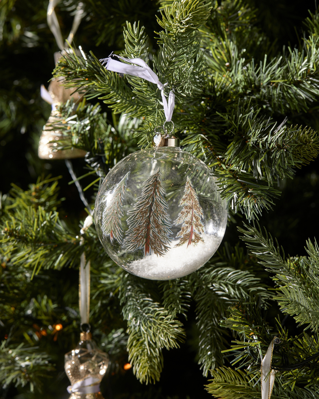 Weihnachtsbaumkugel Christmas Forest Ornament von Rivièra Maison am Tannenbaum mit Schneeeffekt und handbemalten Tannen.
