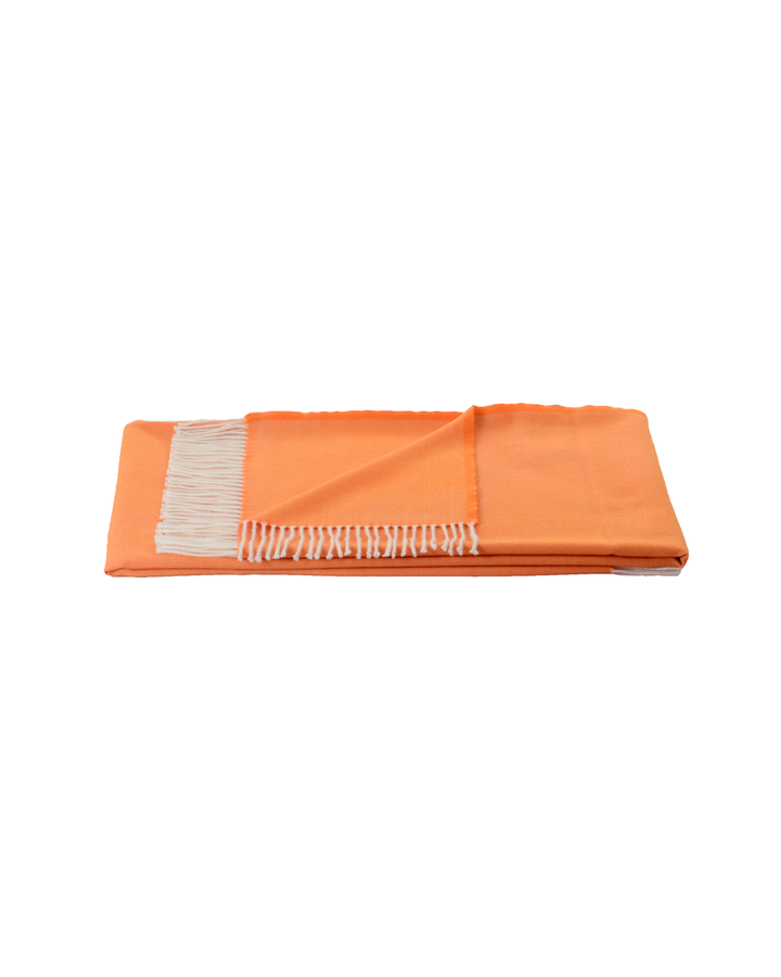 Gefaltete Wolldecke Royal von Steinbeck in leuchtendem Orange mit Fransen, frontal freigestellt