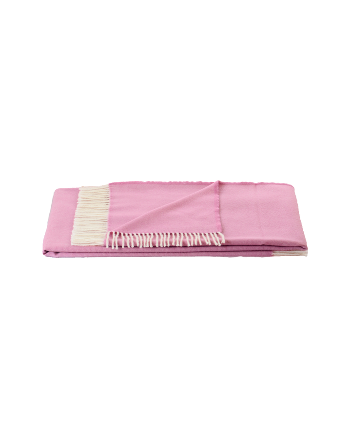 Gefaltete Wolldecke Royal von Steinbeck in Rosa mit hellen Fransen, sauber freigestellte Produktaufnahme