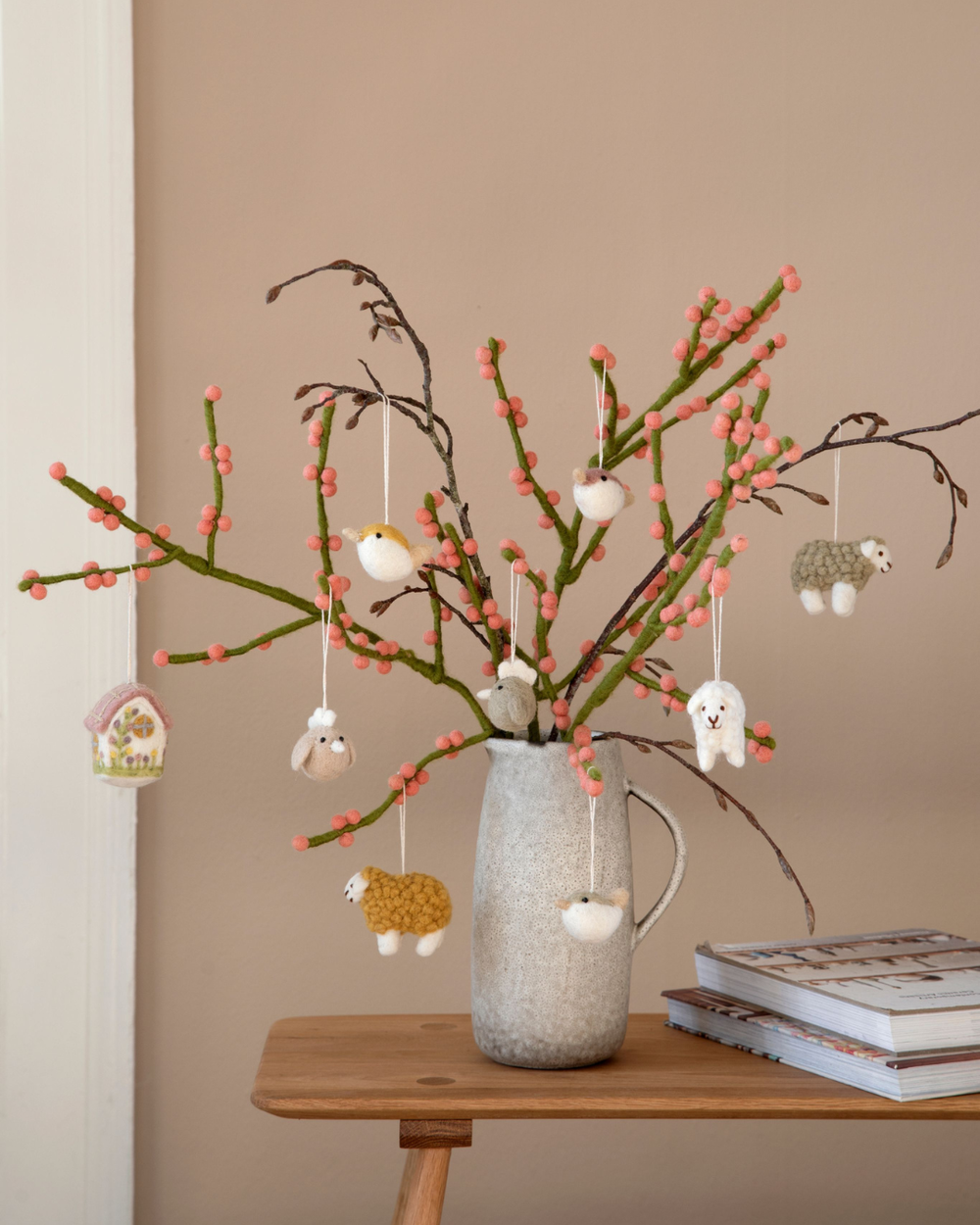 Hühner-Filzanhänger von Gry & Sif dekorativ an blühenden Zweigen in einer Vase arrangiert, kombiniert mit weiteren Filztieren.
